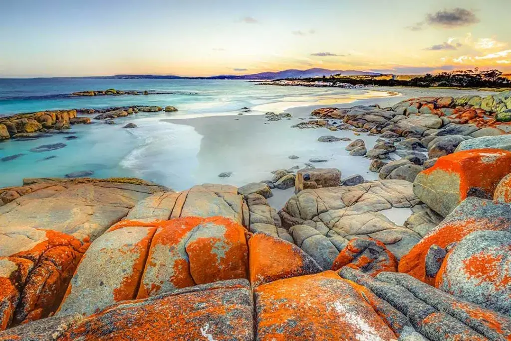 Sunset over the white sands and orange boulders of the Bay of Fires, Tasmania