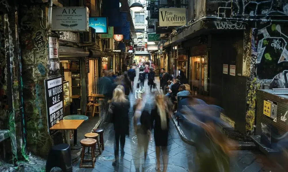 Blurred crowd walking through a graffiti-covered Melbourne laneway.