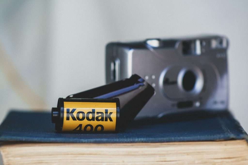 Retro Kodak 400 film roll alongside a vintage camera on a book indoors.